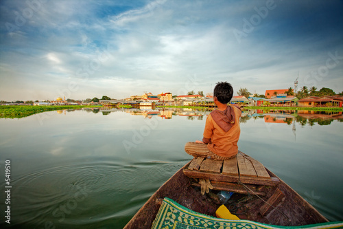 Fotomural Cambodian boy on prow of small boat overlooking lake
