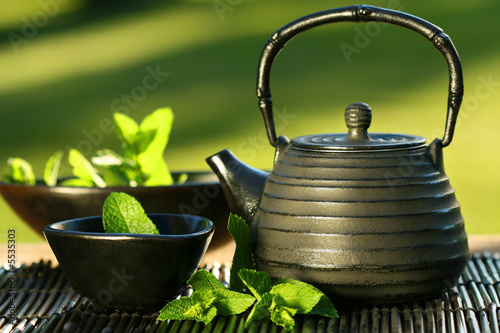 Fototapeta na wymiar Black iron asian teapot with sprigs of mint for tea