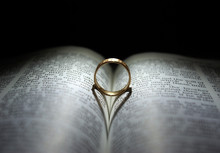 Wedding Ring And Heart Shaped Shadow Over A Bible