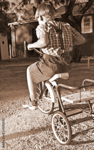 young-boy-in-old-style-clothing-rides-a-tricycle