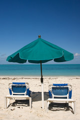 green sun umbrella and two loungers on tropical beach