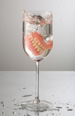 artificial Teeth splashing on wine glass