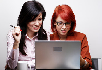 two beautiful women are working at laptop