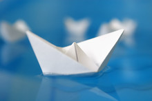 Closeup On One Paper Origami Boat Floating In Blue Water