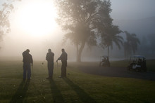 Early Morning Golfers Silhouetted In A Dense Fog