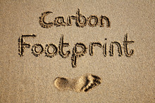 Carbon Footprint Written In Sand On A Beach.