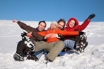 group of friends sit on plastic sled on snow 2