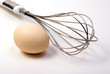 an egg infront of kitchen whisk