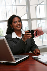 Wall Mural - Businesswoman working on a computer and having coffee