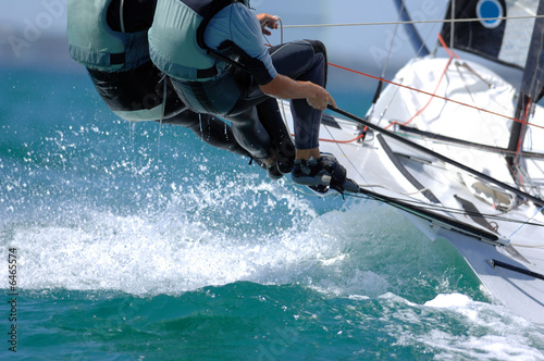 Fotografie, Obraz Sailors splash through the waves during a regatta.
