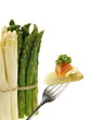 gekochter Spargel mit Butter und Lachs auf einer Gabel und einem Bündel rohen weißen und grünen Spargels im Hintergrund