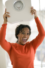 Happy Black woman holding scale