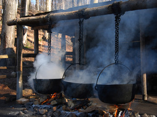 making maple syrup by boiling the sap in a cauldron