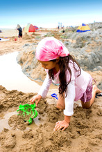 A Young Girl Enjoying Playing In The Sand By The Rockpool 