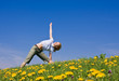 © kubais - young female excercising yoga on flowery meadow