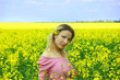 Beautiful girl among blooming rape oilseed field