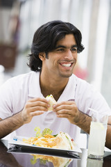 Wall Mural - Man eating sandwiches at cafe