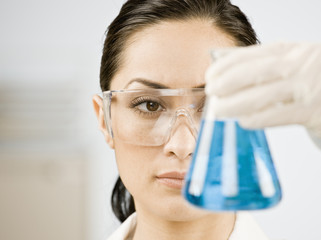 Female scientist looking at beaker of blue liquid