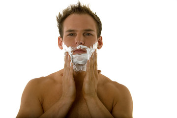 Young man applying shaving cream to his face