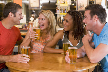 Group of young friends drinking and laughing in a bar