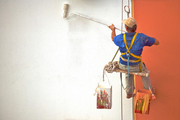 Hanging Painter painting wall with roller