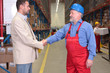 © endostock - manager and older worker hanshake in warehouse