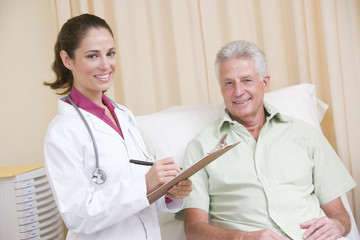 Wall Mural - Doctor writing on clipboard while giving checkup to man in exam