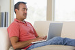 © Monkey Business - Man in living room using laptop and smiling