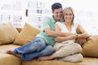 © Monkey Business - Couple in living room with remote control smiling