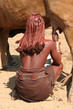 Himba woman is milking a cow, Himba village, Namibia