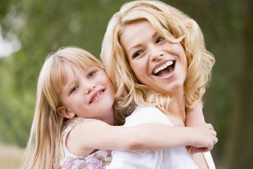 Mother holding daughter outdoors smiling