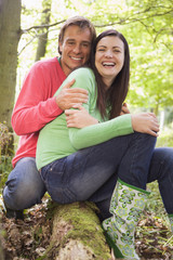 Poster - Couple outdoors in woods sitting on log smiling