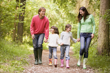 Wall Mural - Family walking on path holding hands smiling