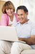 © Monkey Business - Couple in living room with laptop smiling