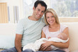 © Monkey Business - Couple in living room with baby smiling