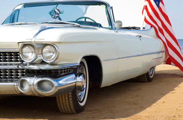 Classic white Cadillac at the beach with American flag