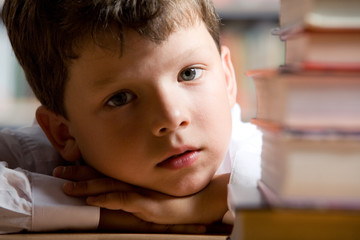 Canvas Print - Close-up of little boy’s face with pile of books near by