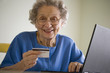 Smiling senior woman using credit card and laptop