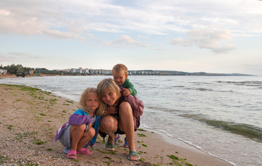 mother with small girl and boy on sandy sea coast