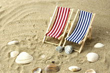 Two Beach Chairs On The Sand Surrounded By Shells