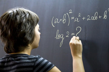 Teacher writing math formulas on blackboard