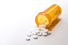 Aspirin Pills Spilling From Medicine Bottle Closeup On White