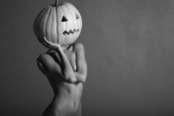 Sexy lady with big pumpkin on head. Surrealstic portrait.