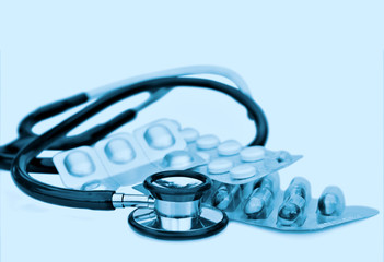 doctors stethoscope and pills in clinical blue