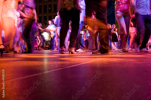 Cuadros en Lienzo The dance floor with people dancing under the colorful lights.