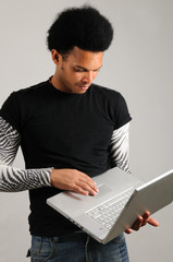 Wall Mural - young trendy latino man holding modern laptop computer