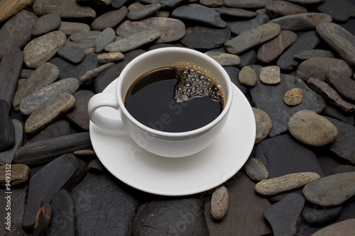 Naklejka na szybę Cup of coffee against black stones and reed sugar