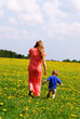 Young woman with her son outgoing in dandelion field