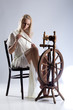 Young attractive woman with a spindle and spinning wheel