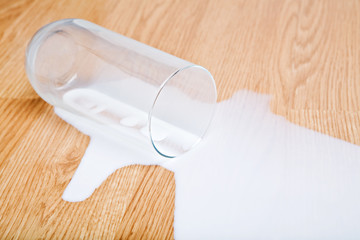 milk spilled from glass on oak wooden surface